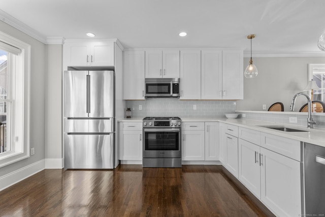 kitchen featuring appliances with stainless steel finishes, decorative light fixtures, white cabinetry, tasteful backsplash, and sink