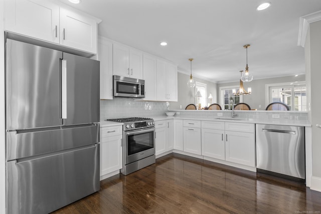 kitchen with decorative light fixtures, decorative backsplash, sink, white cabinetry, and appliances with stainless steel finishes