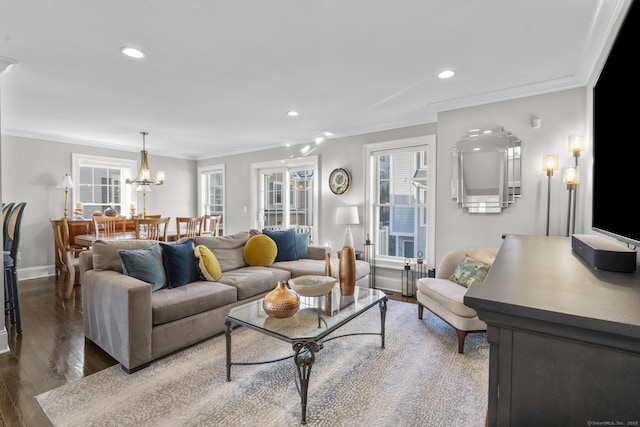 living room featuring a healthy amount of sunlight, dark hardwood / wood-style flooring, crown molding, and an inviting chandelier