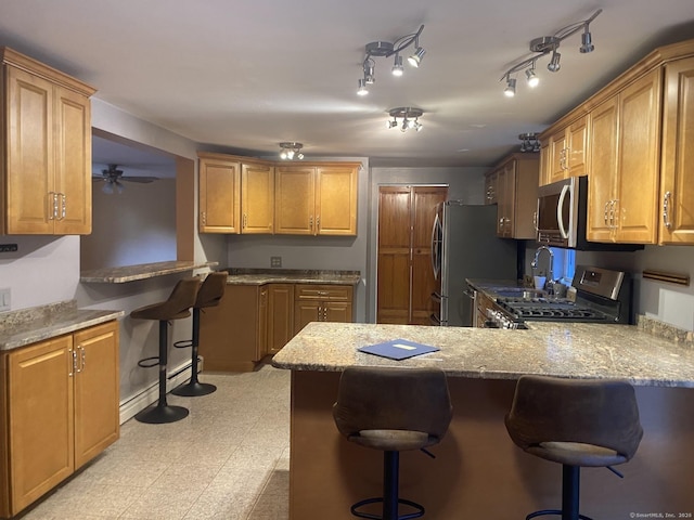 kitchen with ceiling fan, stainless steel appliances, a kitchen bar, and kitchen peninsula