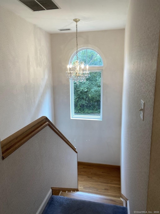 stairs featuring hardwood / wood-style flooring and an inviting chandelier