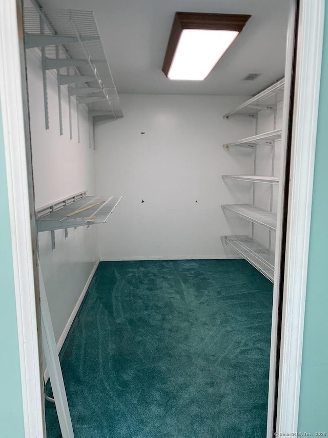 walk in closet featuring dark colored carpet