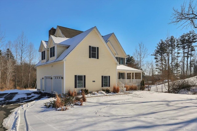 view of snowy exterior with a garage and a sunroom