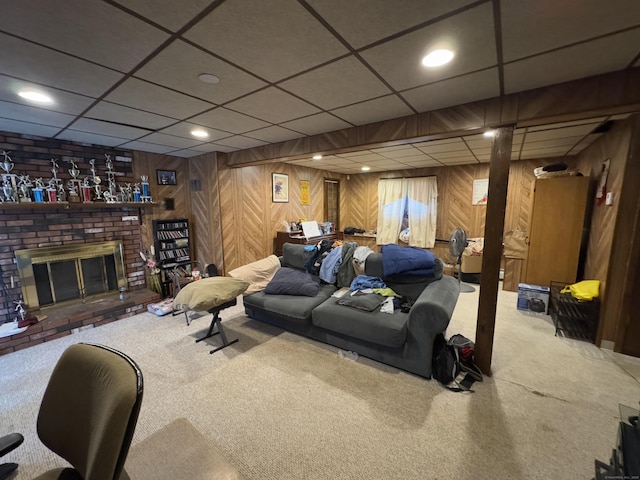 carpeted living room featuring a brick fireplace, a paneled ceiling, and wood walls