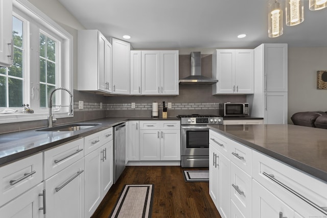 kitchen featuring white cabinetry, wall chimney range hood, and stainless steel appliances