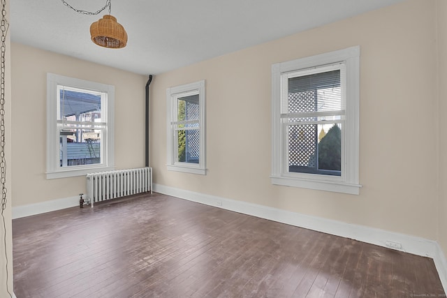 empty room with radiator and dark hardwood / wood-style flooring