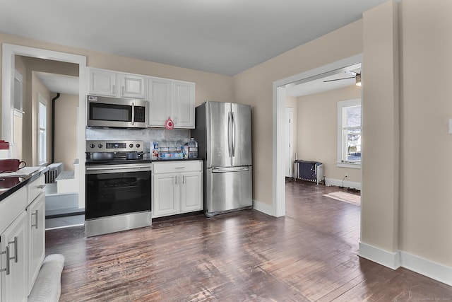 kitchen with white cabinetry, stainless steel appliances, decorative backsplash, dark hardwood / wood-style floors, and ceiling fan