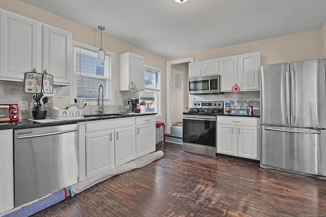 kitchen featuring stainless steel appliances, tasteful backsplash, hanging light fixtures, white cabinets, and sink