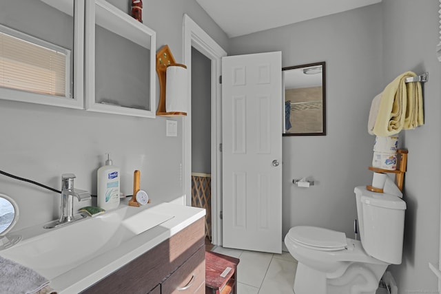 bathroom with toilet, vanity, and tile patterned flooring