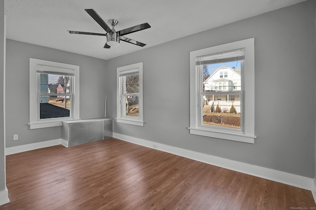 empty room featuring ceiling fan, hardwood / wood-style floors, and radiator