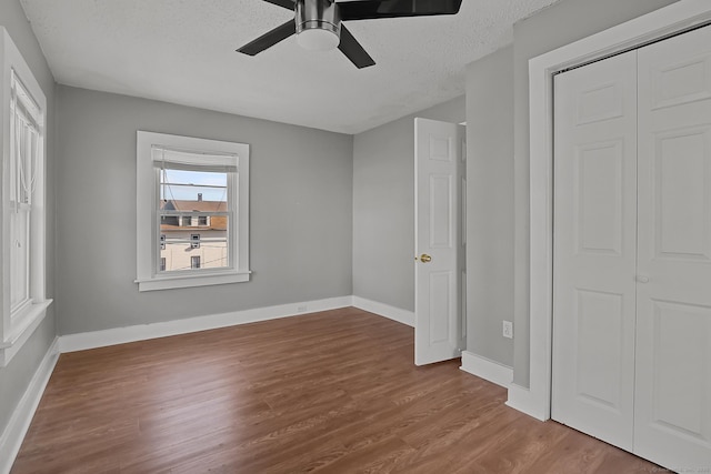 unfurnished bedroom featuring ceiling fan, a closet, a textured ceiling, and hardwood / wood-style floors