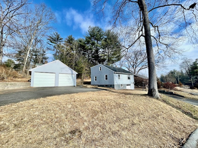 exterior space featuring an outbuilding, a detached garage, and a front yard