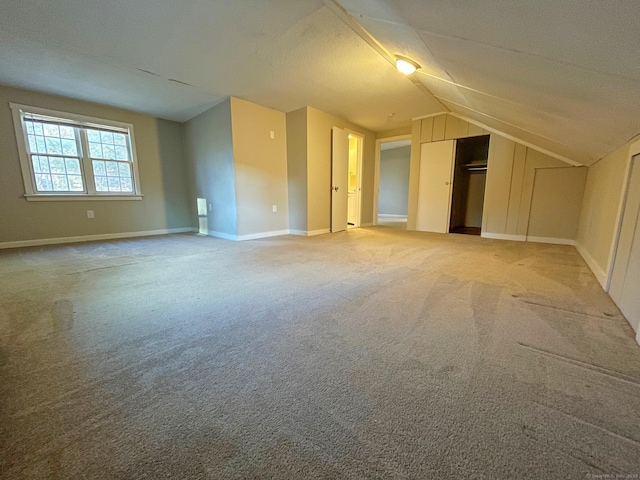 additional living space featuring vaulted ceiling, carpet flooring, and baseboards