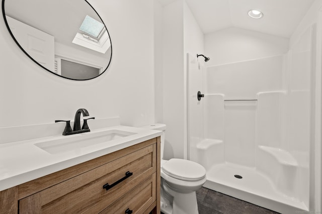 bathroom with vaulted ceiling with skylight, toilet, walk in shower, and vanity