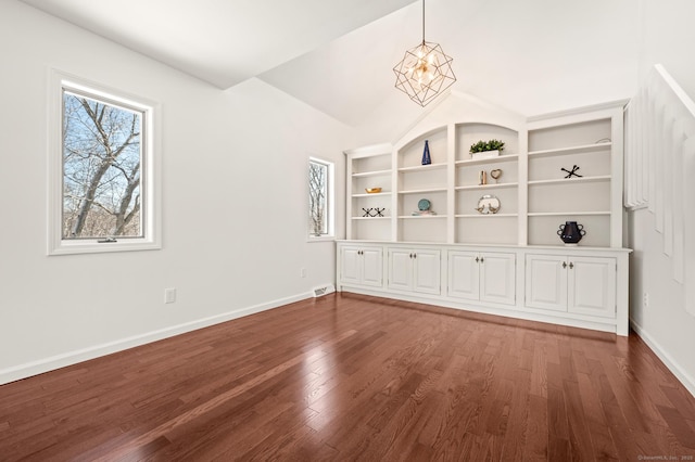 unfurnished room with dark hardwood / wood-style floors, built in features, lofted ceiling, and a notable chandelier