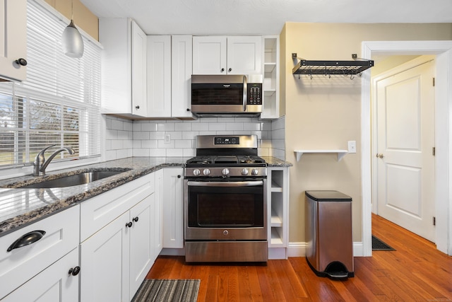 kitchen with decorative backsplash, sink, hanging light fixtures, stainless steel appliances, and white cabinets