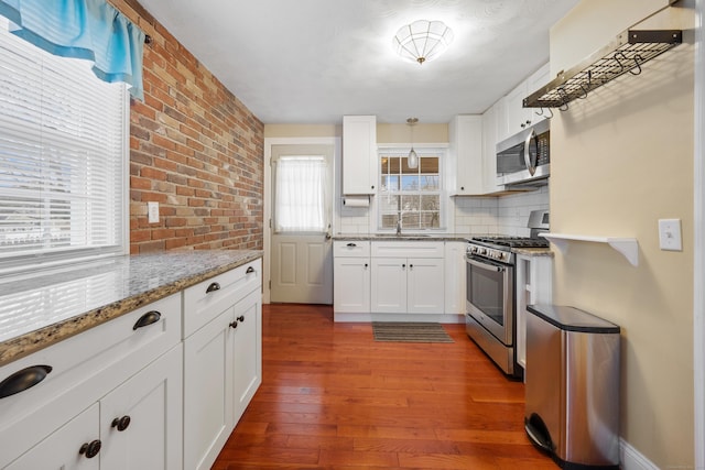 kitchen featuring dark hardwood / wood-style floors, stainless steel appliances, decorative backsplash, and white cabinetry