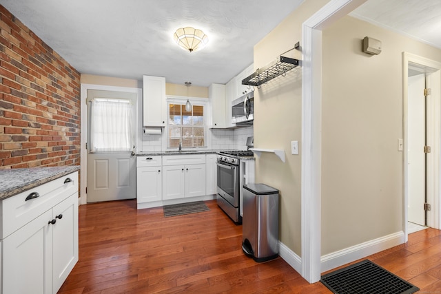 kitchen featuring decorative backsplash, light stone counters, white cabinetry, and stainless steel appliances