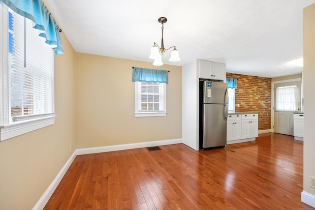 kitchen with hardwood / wood-style flooring, white cabinetry, and stainless steel fridge