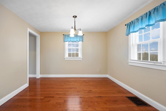 unfurnished dining area with wood-type flooring and an inviting chandelier