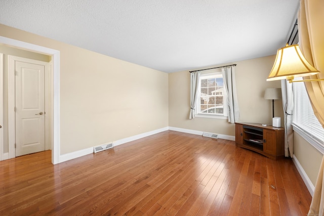 unfurnished room featuring hardwood / wood-style flooring and a textured ceiling