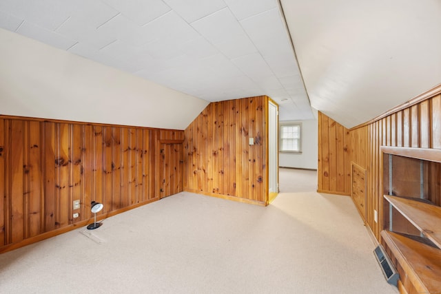 additional living space featuring carpet, vaulted ceiling, and wooden walls