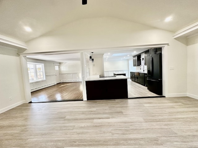 kitchen featuring black refrigerator, a baseboard heating unit, light hardwood / wood-style flooring, and sink