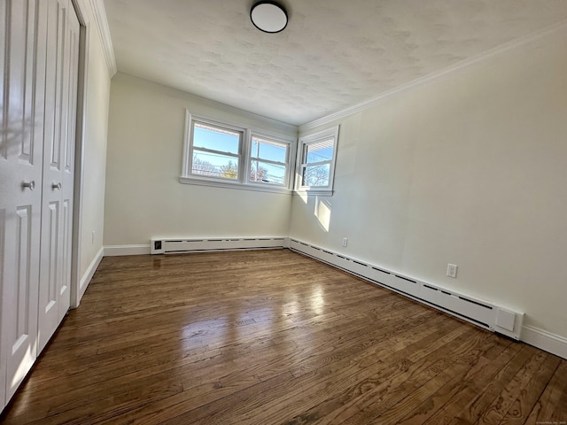 unfurnished bedroom featuring baseboard heating, ornamental molding, dark hardwood / wood-style floors, and a textured ceiling