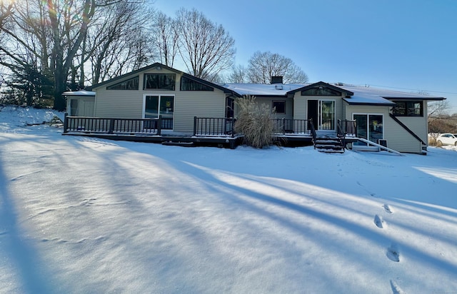 snow covered back of property with a deck