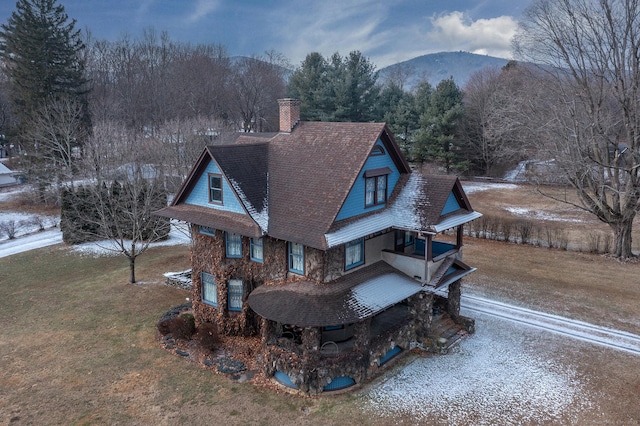 view of front of property with a mountain view, a shingled roof, driveway, a front lawn, and a chimney