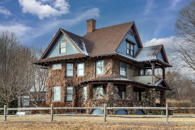 view of front of house with a fenced front yard, a chimney, and roof with shingles