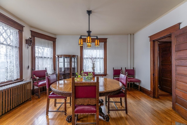 dining area with ornamental molding, baseboards, light wood-style flooring, and radiator heating unit