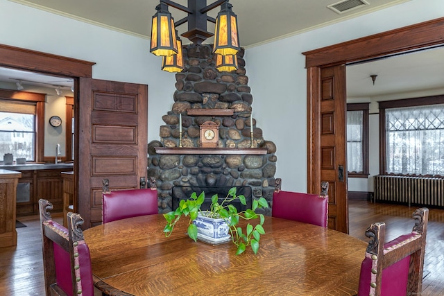 dining area with a stone fireplace, ornamental molding, visible vents, and radiator