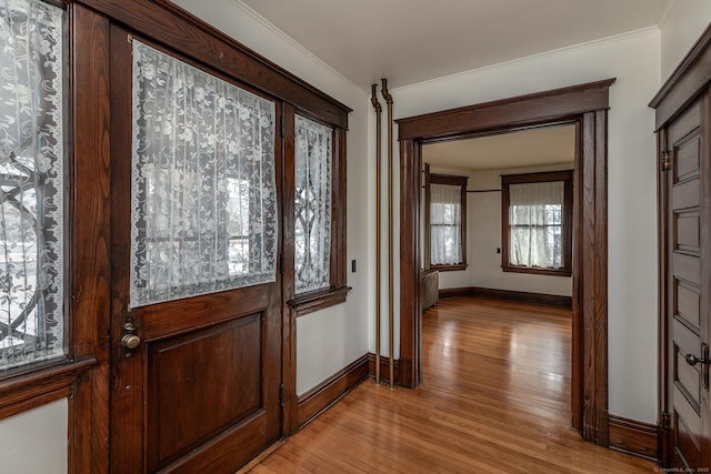 interior space with crown molding, light wood-style flooring, and baseboards