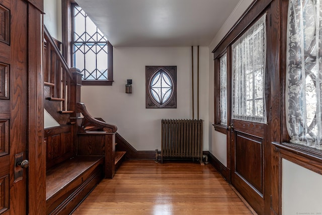 entrance foyer with radiator, light wood finished floors, stairs, and baseboards