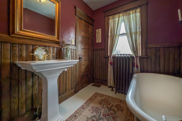 bathroom featuring a wainscoted wall, a freestanding bath, radiator heating unit, and wooden walls