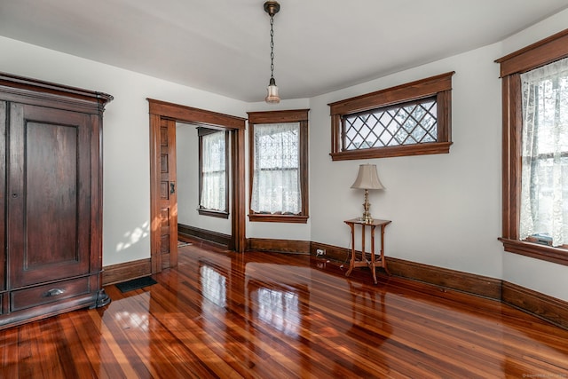 spare room featuring wood-type flooring, visible vents, and baseboards