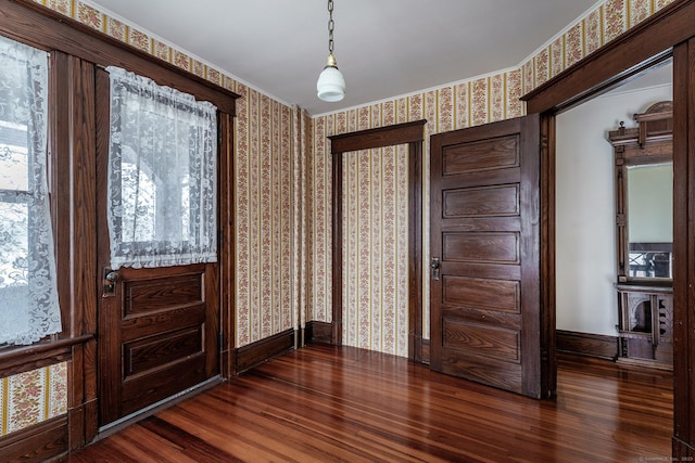 foyer entrance featuring baseboards, wood finished floors, and wallpapered walls