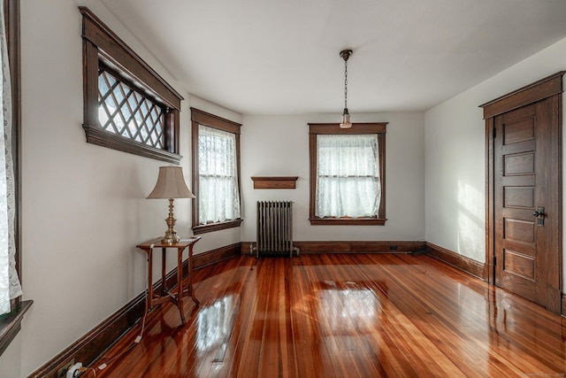 unfurnished living room featuring baseboards, wood-type flooring, and radiator