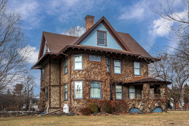 exterior space featuring a shingled roof, a chimney, and a front lawn