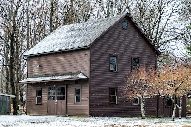 view of snow covered exterior featuring roof with shingles