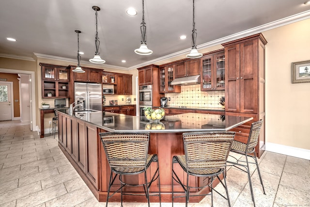 kitchen with appliances with stainless steel finishes, pendant lighting, a breakfast bar area, backsplash, and a spacious island