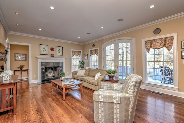 living room featuring a tile fireplace, ornamental molding, hardwood / wood-style floors, and french doors