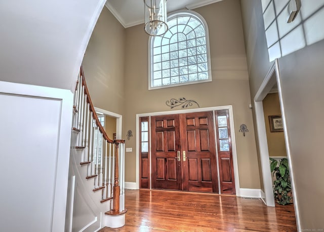 foyer featuring crown molding, a healthy amount of sunlight, hardwood / wood-style floors, and a towering ceiling