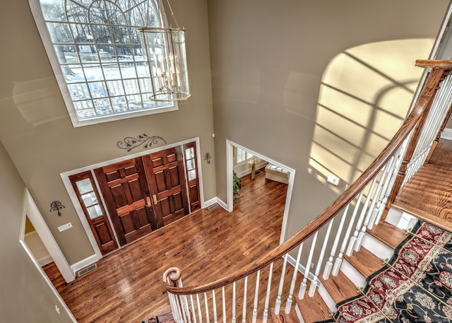 entryway with hardwood / wood-style floors, a notable chandelier, and a high ceiling