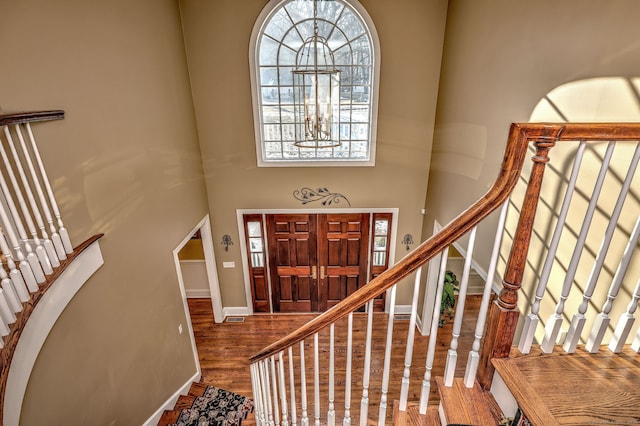 entryway featuring hardwood / wood-style flooring, a towering ceiling, and a notable chandelier