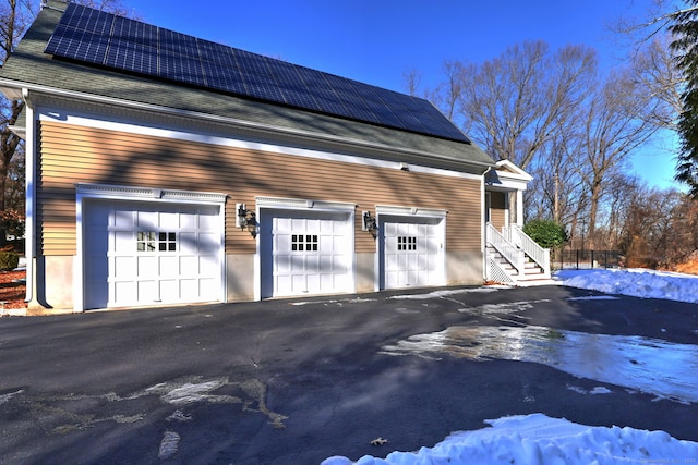 snow covered garage with solar panels