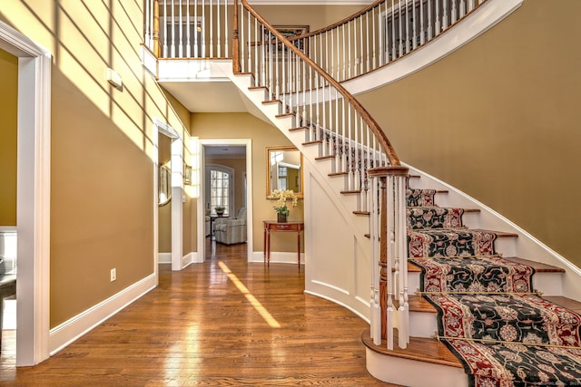 foyer with wood-type flooring and a towering ceiling