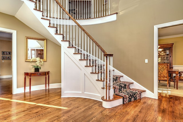 stairs featuring hardwood / wood-style floors and ornamental molding