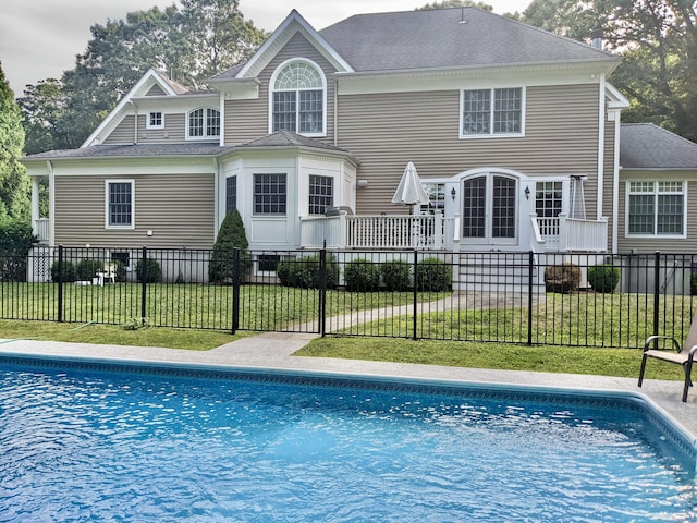 rear view of house featuring a yard and a fenced in pool